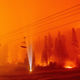 A photographer shines a flashlight towards a chair lift as flames surround Sierra-at-Tahoe Resort, a skiing area, during the Caldor fire in Twin Bridges, California on Aug. 30, 2021